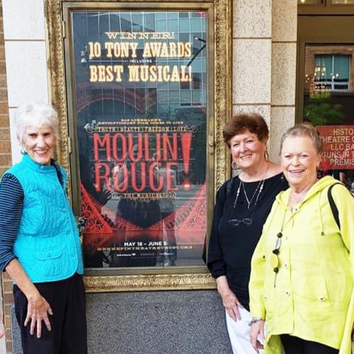 3 older woman standing by moulin rouge poster