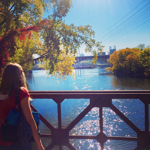 woman looking over bridge and water