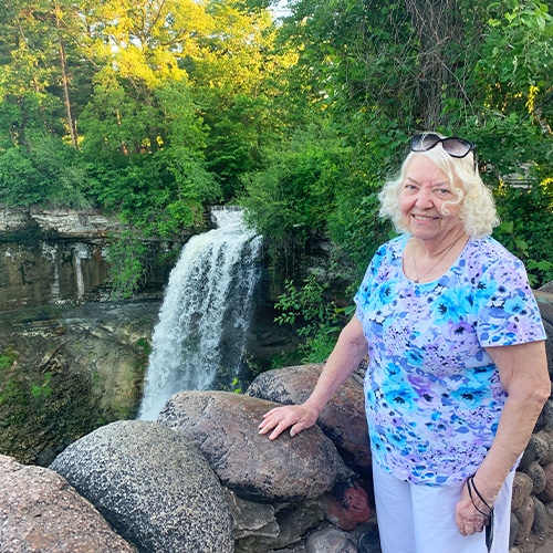 older woman standing near a waterfall