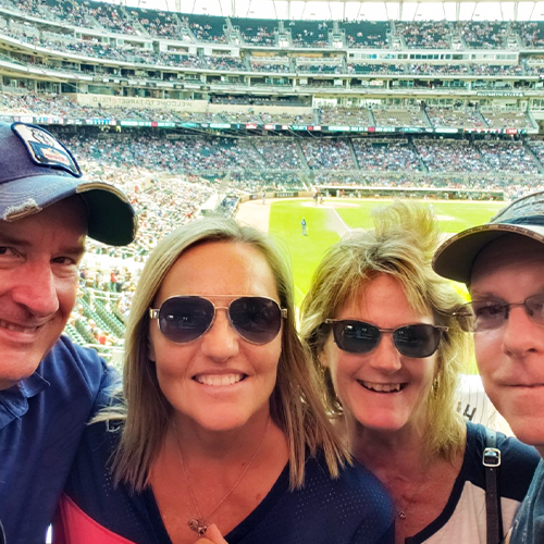 two women and two men with baseball stadium behind them