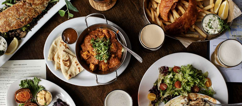 spread of food from brits pub including salad, butter chicken and fish and chips
